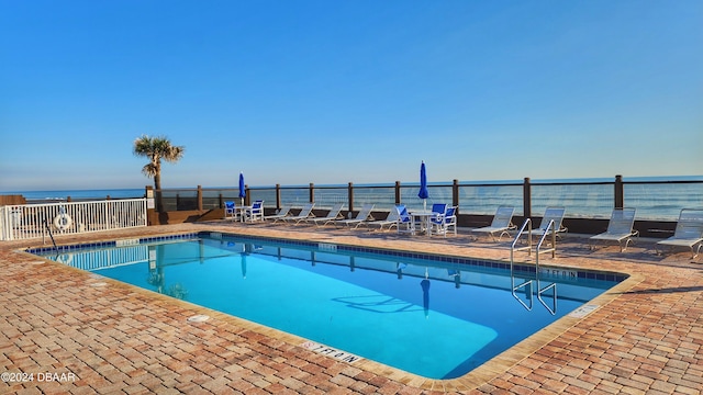 view of pool featuring a water view and a patio