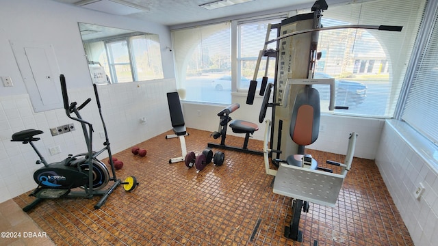 workout room with dark tile patterned flooring and tile walls