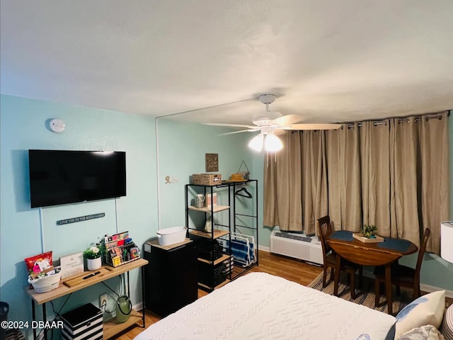 bedroom featuring hardwood / wood-style floors, ceiling fan, and an AC wall unit