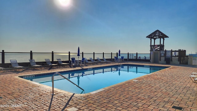 view of swimming pool with a patio area and a water view