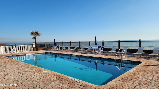 view of swimming pool featuring a water view and a patio