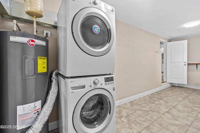 laundry room featuring electric water heater, laundry area, baseboards, stacked washer / drying machine, and tile patterned floors