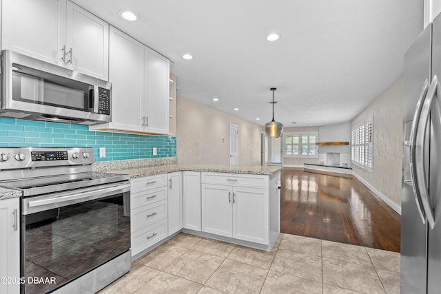 kitchen featuring open floor plan, a peninsula, stainless steel appliances, white cabinetry, and open shelves