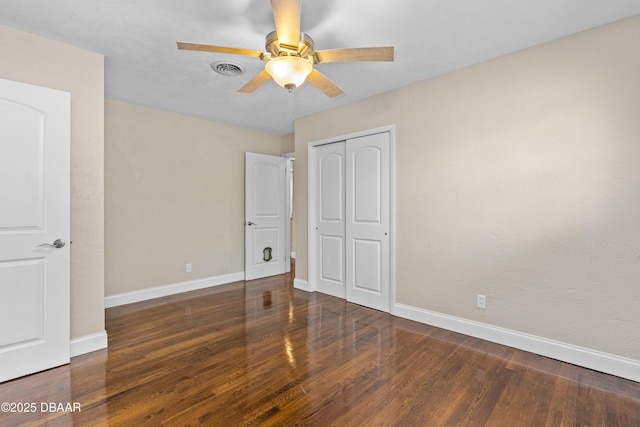 unfurnished bedroom with a closet, visible vents, baseboards, and wood finished floors