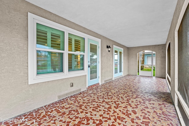 unfurnished sunroom featuring visible vents and arched walkways