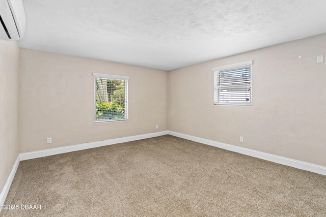 carpeted empty room featuring a textured ceiling, an AC wall unit, and baseboards