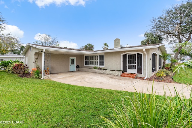 rear view of property with entry steps, a yard, a chimney, and stucco siding