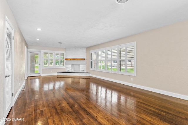 unfurnished living room with a brick fireplace, recessed lighting, wood-type flooring, and baseboards