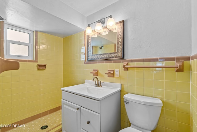 full bathroom with tiled shower, tile walls, toilet, and vanity