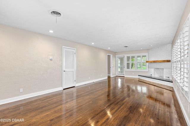 unfurnished living room with recessed lighting, visible vents, a brick fireplace, wood finished floors, and baseboards