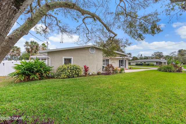 view of home's exterior with fence, a lawn, and stucco siding