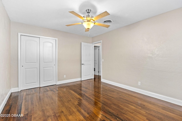 unfurnished bedroom featuring baseboards, wood-type flooring, visible vents, and a closet