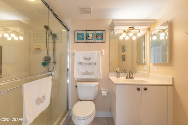 bathroom featuring tile patterned floors, vanity, toilet, and a shower with door