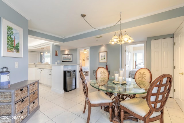 tiled dining area with ceiling fan with notable chandelier, beverage cooler, and crown molding