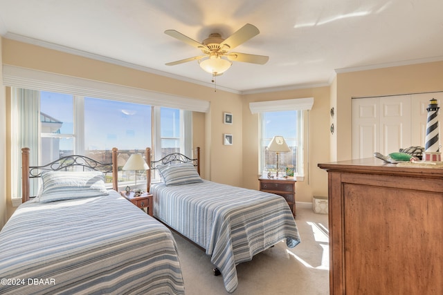 bedroom featuring ceiling fan, a closet, light colored carpet, and ornamental molding