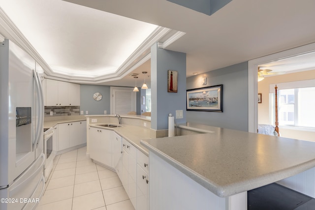 kitchen with backsplash, white appliances, sink, decorative light fixtures, and white cabinets