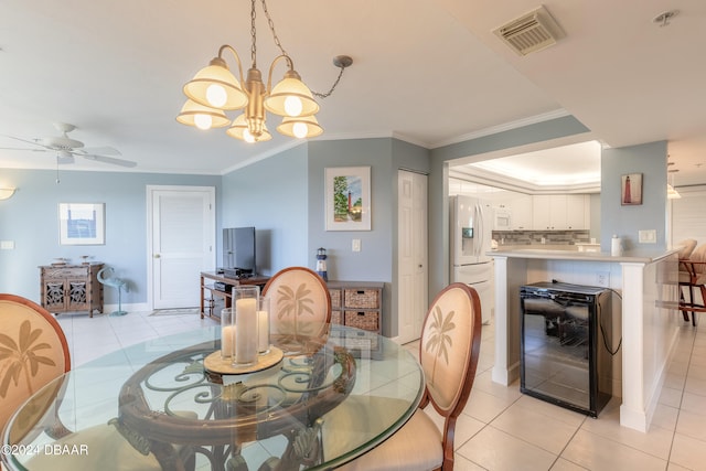 tiled dining space with ceiling fan with notable chandelier, ornamental molding, and beverage cooler