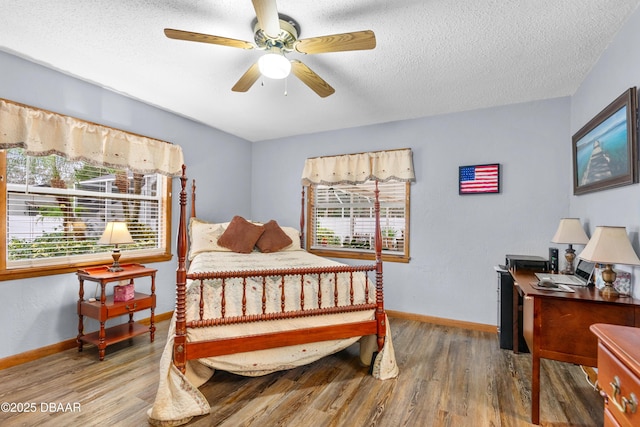 bedroom with ceiling fan, wood-type flooring, and a textured ceiling