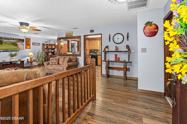 living room with ceiling fan, dark wood-type flooring, and a textured ceiling