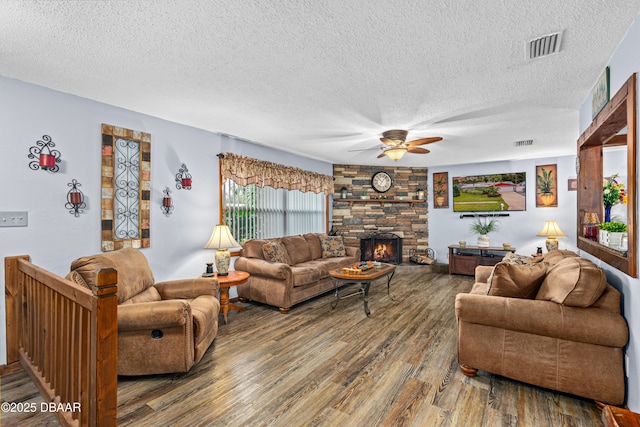 living room with a textured ceiling, ceiling fan, a fireplace, and hardwood / wood-style floors