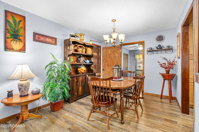 dining space featuring ceiling fan with notable chandelier, a textured ceiling, and light hardwood / wood-style floors