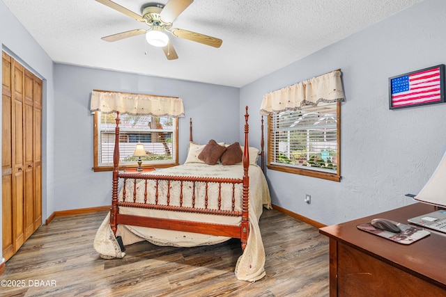 bedroom featuring ceiling fan, a closet, hardwood / wood-style flooring, and multiple windows