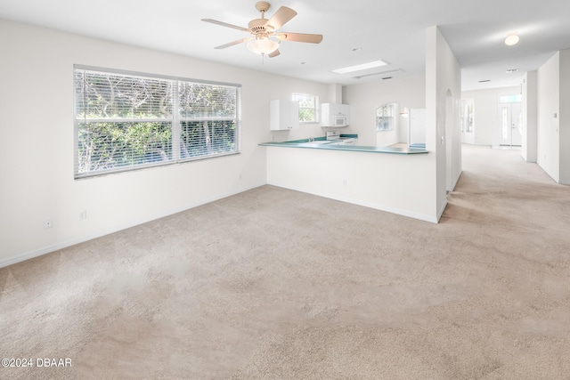 kitchen featuring white cabinets, ceiling fan, and light colored carpet