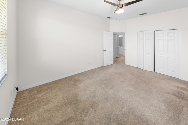 unfurnished bedroom with ceiling fan, a closet, and light colored carpet