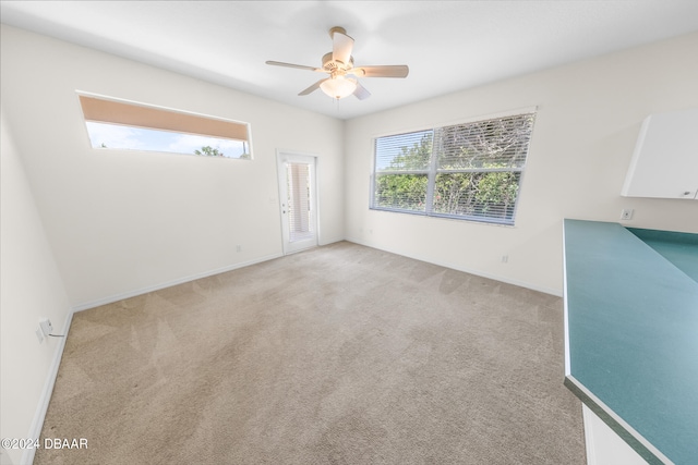 spare room with ceiling fan and light carpet