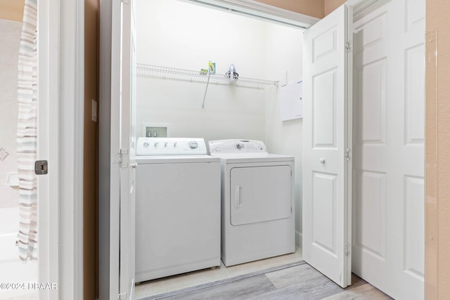 laundry room featuring washing machine and dryer and light hardwood / wood-style floors