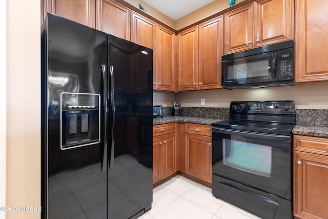 kitchen featuring dark stone counters, light tile patterned floors, and black appliances