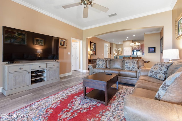 living room featuring ceiling fan with notable chandelier, light hardwood / wood-style flooring, and crown molding