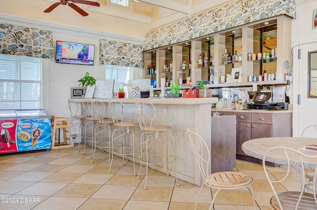 bar featuring light tile patterned floors, ceiling fan, and plenty of natural light