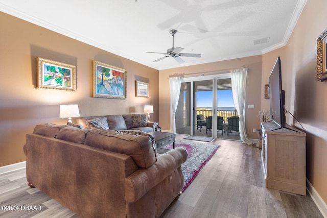 living room featuring ornamental molding, light wood-type flooring, and ceiling fan