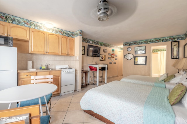 bedroom featuring sink, ceiling fan, white fridge, and light tile patterned floors