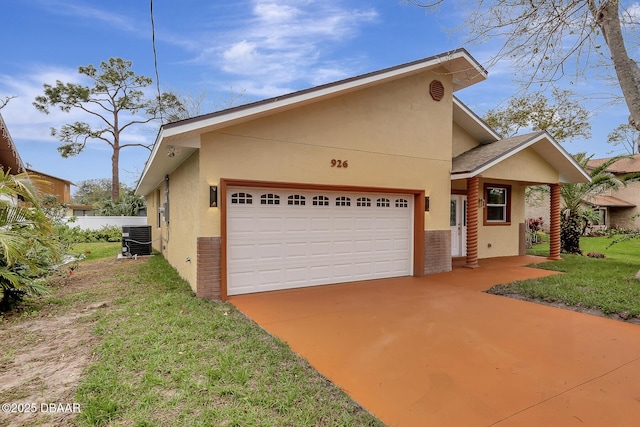 view of front of property featuring a garage, a front yard, central AC, and stucco siding