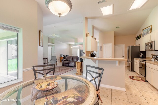 tiled dining area featuring ceiling fan and vaulted ceiling