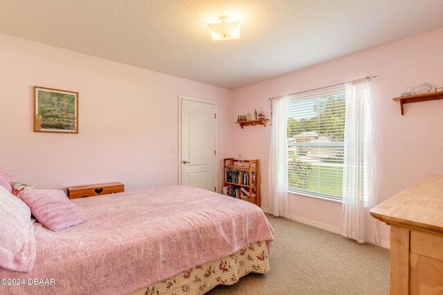 bedroom with a textured ceiling and light carpet