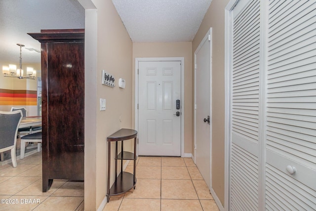 corridor with a notable chandelier, a textured ceiling, and light tile patterned flooring