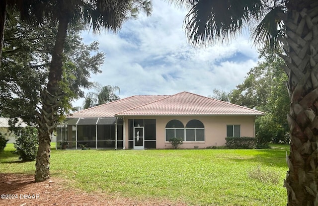 rear view of property featuring a lawn and glass enclosure