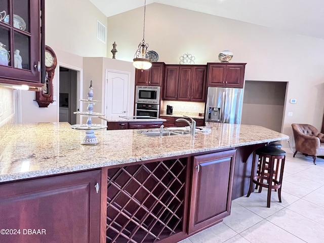 kitchen with stainless steel appliances, light stone countertops, sink, and hanging light fixtures