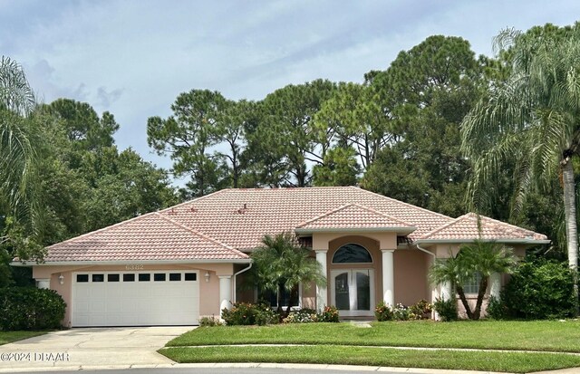 6382 Longlake Dr, Port Orange, FL 32128 - mediterranean / spanish-style home with an attached garage, concrete driveway, a front lawn, and stucco siding