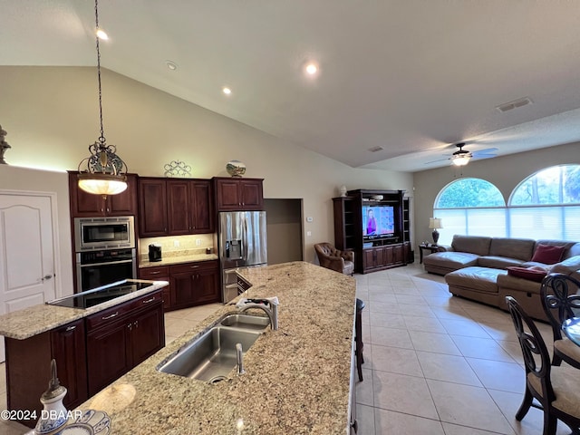 kitchen featuring sink, decorative light fixtures, a center island with sink, appliances with stainless steel finishes, and light stone countertops