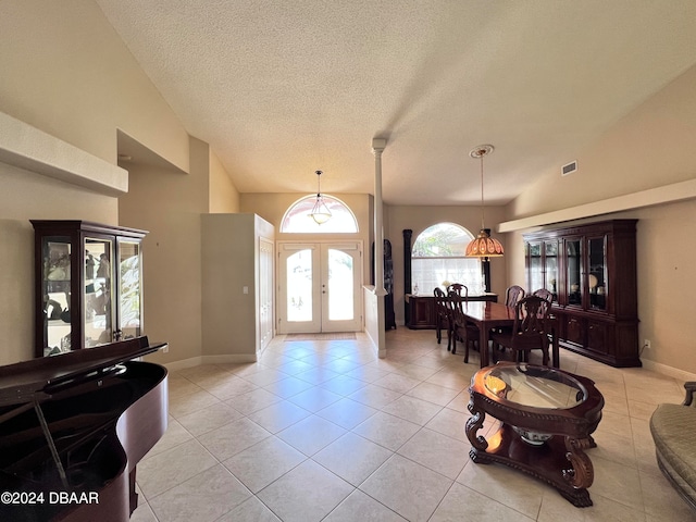 tiled foyer entrance with lofted ceiling, a textured ceiling, and french doors