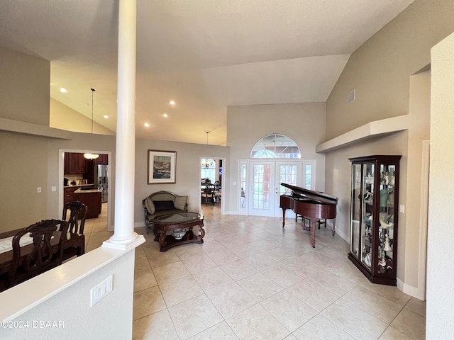 living room featuring high vaulted ceiling, light tile patterned flooring, french doors, and ornate columns