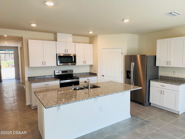 kitchen featuring sink, appliances with stainless steel finishes, white cabinetry, a kitchen bar, and a center island with sink