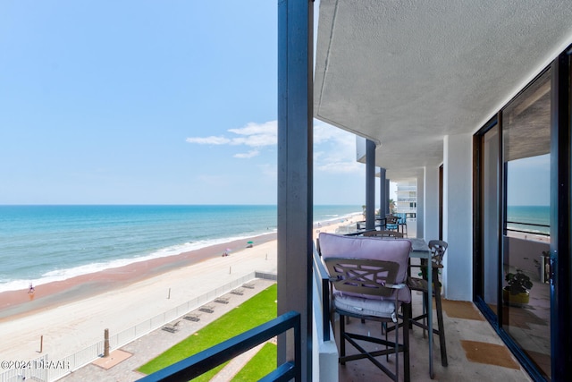 balcony with a water view and a view of the beach