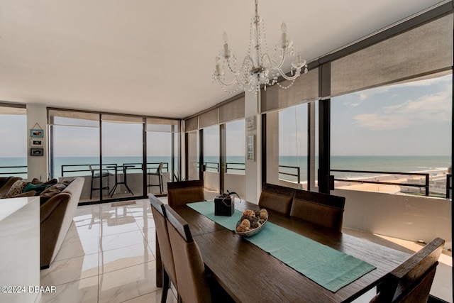 dining area with a water view, a beach view, and an inviting chandelier