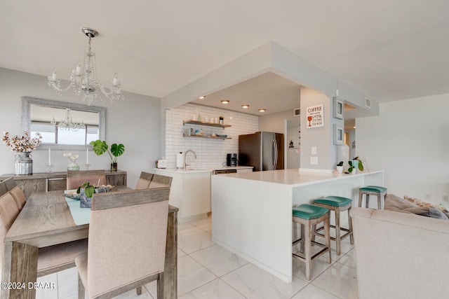 kitchen featuring stainless steel fridge, a breakfast bar, sink, decorative light fixtures, and a notable chandelier