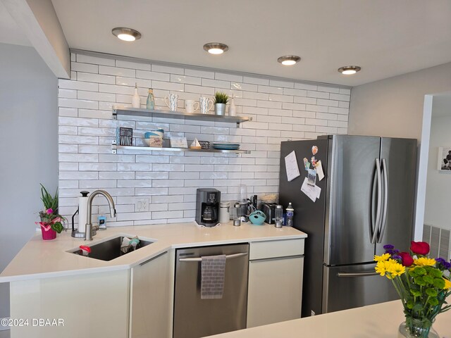 kitchen with kitchen peninsula, appliances with stainless steel finishes, backsplash, and sink